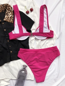 Set bikini fucsia con scollo a U e slip a vita alta su sfondo di tessuto bianco piatto