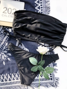 Flat lay of black drawstring bikini set with ruched bandeau top and matching bottoms