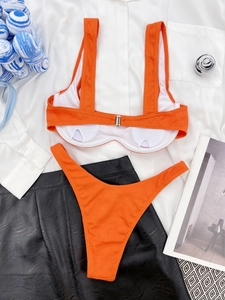 Flat lay of orange ribbed bikini set with wide straps and metal clasp details