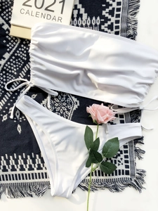 Flat lay of white two-piece bikini with drawstring bandeau top on textured blanket