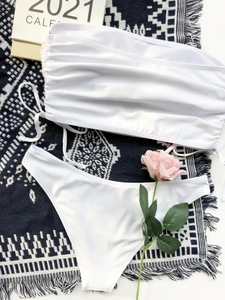 Flat lay of white drawstring bikini set with side-tie details on a blue textured rug