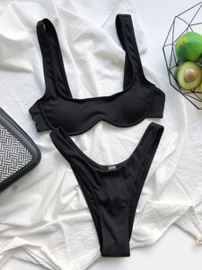 Flat lay of black ribbed bikini set with U-neck top and summer vacation props