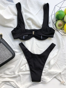 Detailed view of black ribbed bikini set with U-neck top and high-cut bottoms on linen