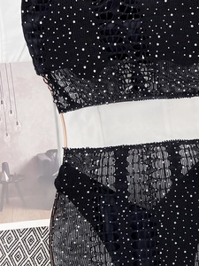 Détail d'un bikini en crochet noir avec strass brillants sur un cintre doré chic