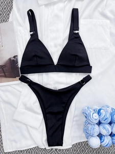 Detail of black ribbed fabric bikini with metal rings on white shirt background