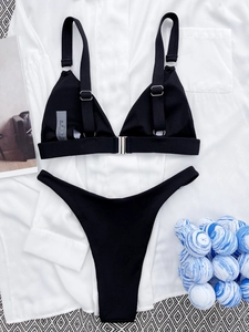 Detailed flat lay of ribbed black bikini with silver buckle and decorative magazines