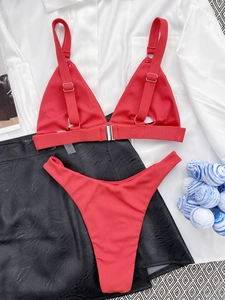 Flat lay of red ribbed bikini set with metal rings on marble and silk background