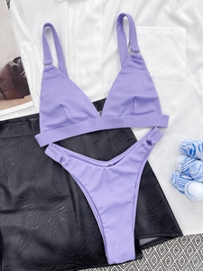 Flat lay of purple ribbed bikini set with triangle top and high-cut bottom on fashion props