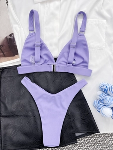 Detailed flat lay of purple ribbed bikini set with metal buckle and beach accessories