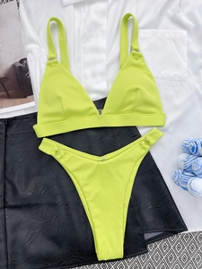 Detailed flat lay of a neon green ribbed bikini set with metal rings on white fabric