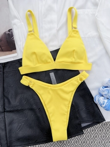 Detailed view of yellow ribbed bikini texture with adjustable straps and metal ring details