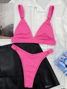 Detail of hot pink ribbed bikini with silver metal ring accents on a flat lay set