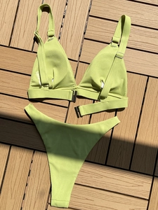 Detail of lime green ribbed bikini set with metal buckle on wood background