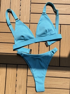 Detail of light blue ribbed bikini fabric texture with metal ring and wood background