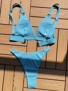 Detail view of bright blue ribbed bikini fabric with metallic ring buckle accents