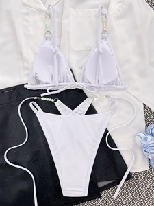 Close-up of white bikini with luxury iridescent beads and material composition label