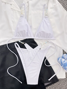 Close-up of white bikini top with gradient beads and high-cut cross-strap bottoms