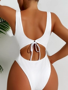 Detail of white ribbed one-piece swimsuit featuring a back cutout and tie-up bow detail