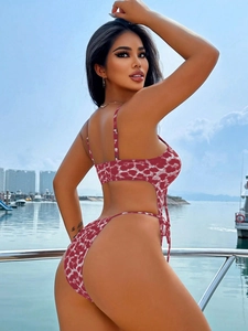 Detail of red polka dot monokini with side cut-outs and lace-up back on yacht deck