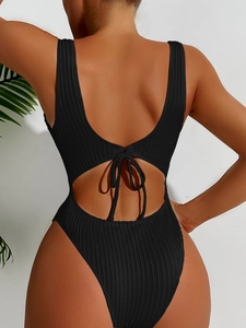 Detail of black rib-knit swimsuit featuring backless cutout and bow-tie ribbon design