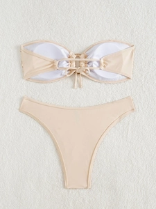 Detail of beige bandeau bikini top with central ring connector and padded cups on soft fur