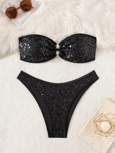 Two-piece black sequined bikini set with bandeau top and golden ring detail on plush background