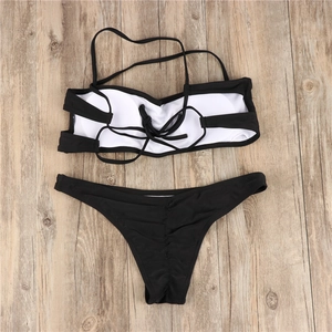 Flat lay of black two-piece bikini with bandeau top and ruched bottoms on wood background