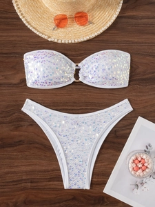 Two-piece shimmering sequin bikini set with bandeau top and ring detail on dark wood