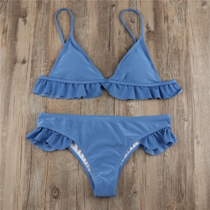 Flat lay of sky blue bikini set with ruffle details on wooden background