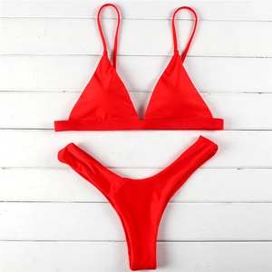 Vibrant red two-piece bikini set with triangle top and high-cut thong on white wood