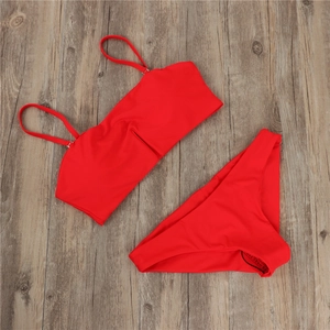 Flat lay of red two-piece bikini set with bandeau top on rustic wooden background
