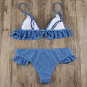 Detailed view of blue bikini set with ruffle trims and removable soft pads on wooden background