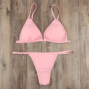 Flat lay of pink halter bikini set with thong bottoms on a vintage wooden background