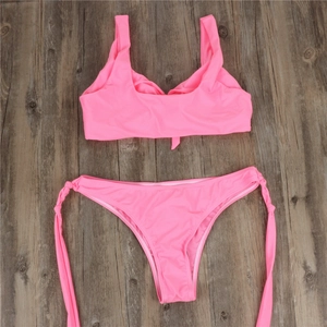 Detailed flat lay of a vibrant pink bikini set featuring wide straps and side-tie bottoms