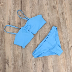Flat lay of sky blue bandeau bikini set with thin straps on wooden background