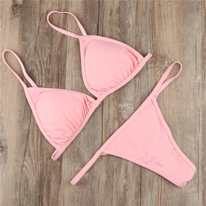 Flat lay of pink two-piece halter bikini set on a brown wooden texture background