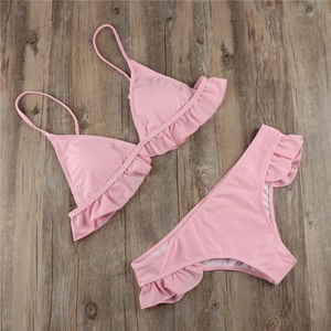 Close-up of pink two-piece bikini set with ruffle details on high-quality wood background