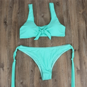 Flat lay of mint green two-piece bikini featuring a front knot and side-tie swim bottoms