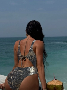 Detailed view of sparkly one-piece swimsuit featuring open back and waist tie details