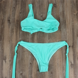 Detailed flat lay of a mint green bikini set with wide straps on dark wood background