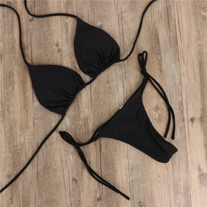 Flach liegendes schwarzes Bikini-Set mit verstellbaren Trägern auf einem Holzgrund