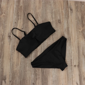 Detailed flat lay of a black bandeau bikini set with adjustable straps on wooden surface