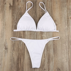 Flat lay of a white two-piece bikini set with halter top on natural wood background