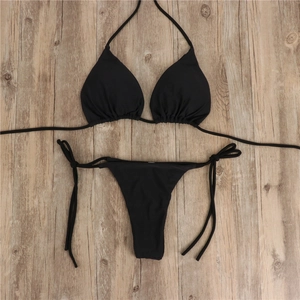 Flatlay eines schwarzen Bikini-Sets mit Triangel-Oberteil und Schnürhose auf Holzgrund