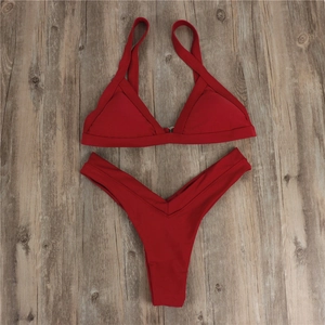 Flat lay of a red two-piece bikini set with halter top on a dark rustic wooden floor