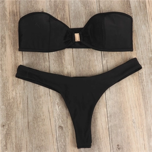 Flat lay of black bandeau bikini top with golden rectangular metal buckle and thong bottom