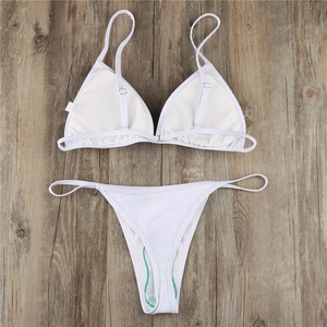 Flat lay of white triangle bikini set with adjustable straps on wooden background