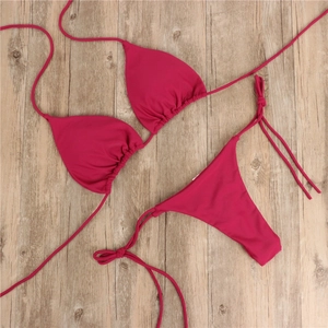 Detailansicht eines rose-roten Triangel-Bikini-Sets mit seitlicher Schnürung auf Holz
