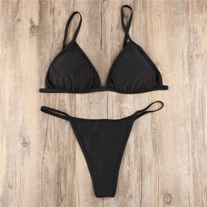 Detailed flat lay of a black two-piece bikini set with thin straps on wooden background