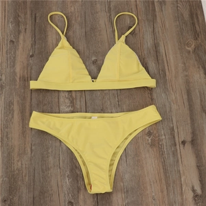 Detailed flat lay of a two-piece yellow triangle bikini set on a wooden background